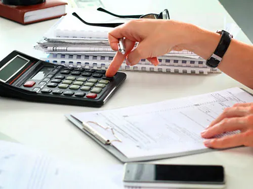Pessoa calculando o imposto de renda com documentos e calculadora