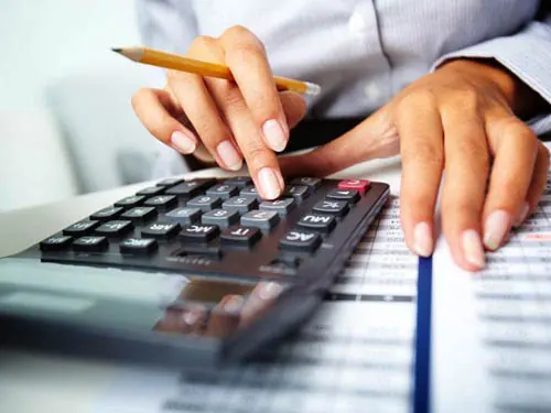 Profissional calculando o imposto de renda da empresa com calculadora e relatórios
